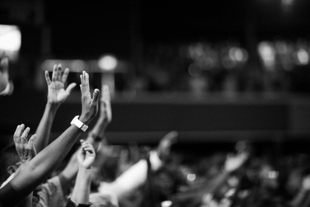 Black and white image of audience with hands raised, capturing concert energy.